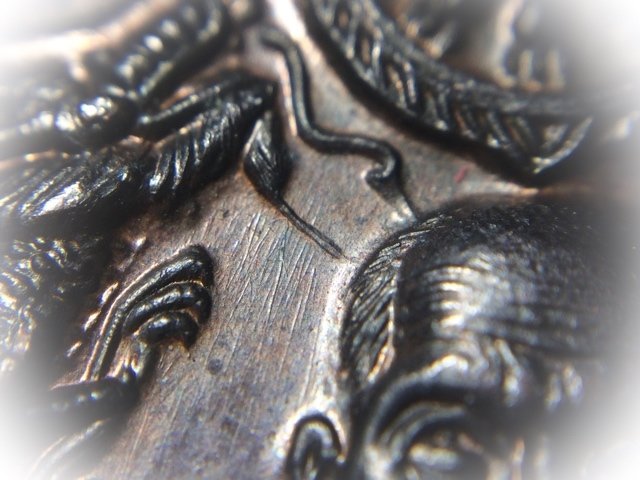 A thin line of extra metal raised up like a ridge flows from the mouth of the dragon towards the image of Luang Phu, one of the points of recognition for authenticity
